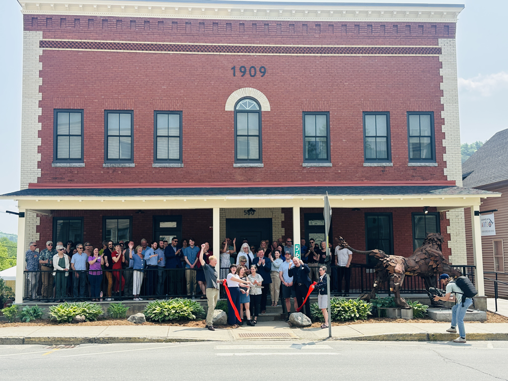 a group of people in front of a brick building at a ribbon cutting ceremony for the building's renovation