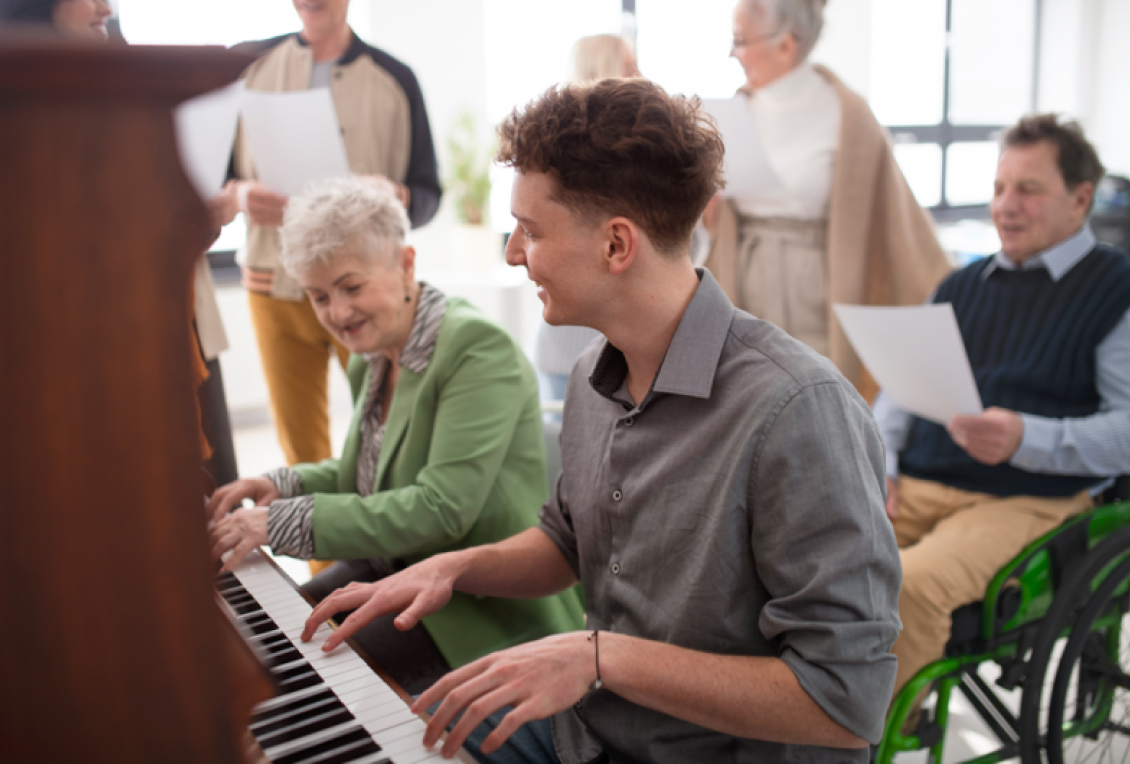 senior and junior citizen playing piano together
