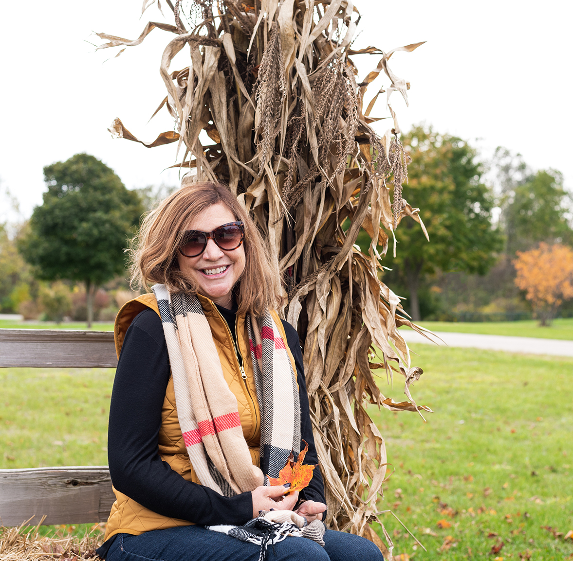 A woman in a scarf sits on a bench during a Vermont fall.