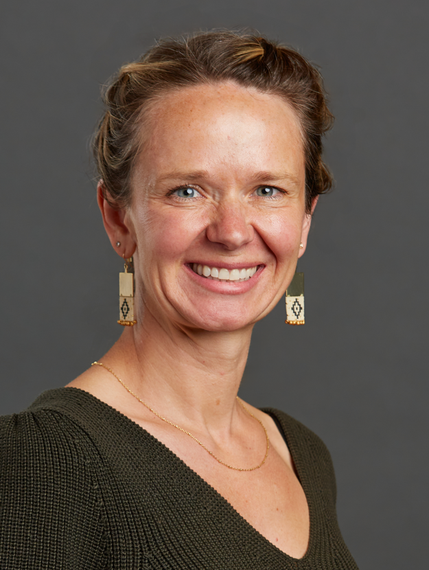 a woman wearing an olive green top and gold earring