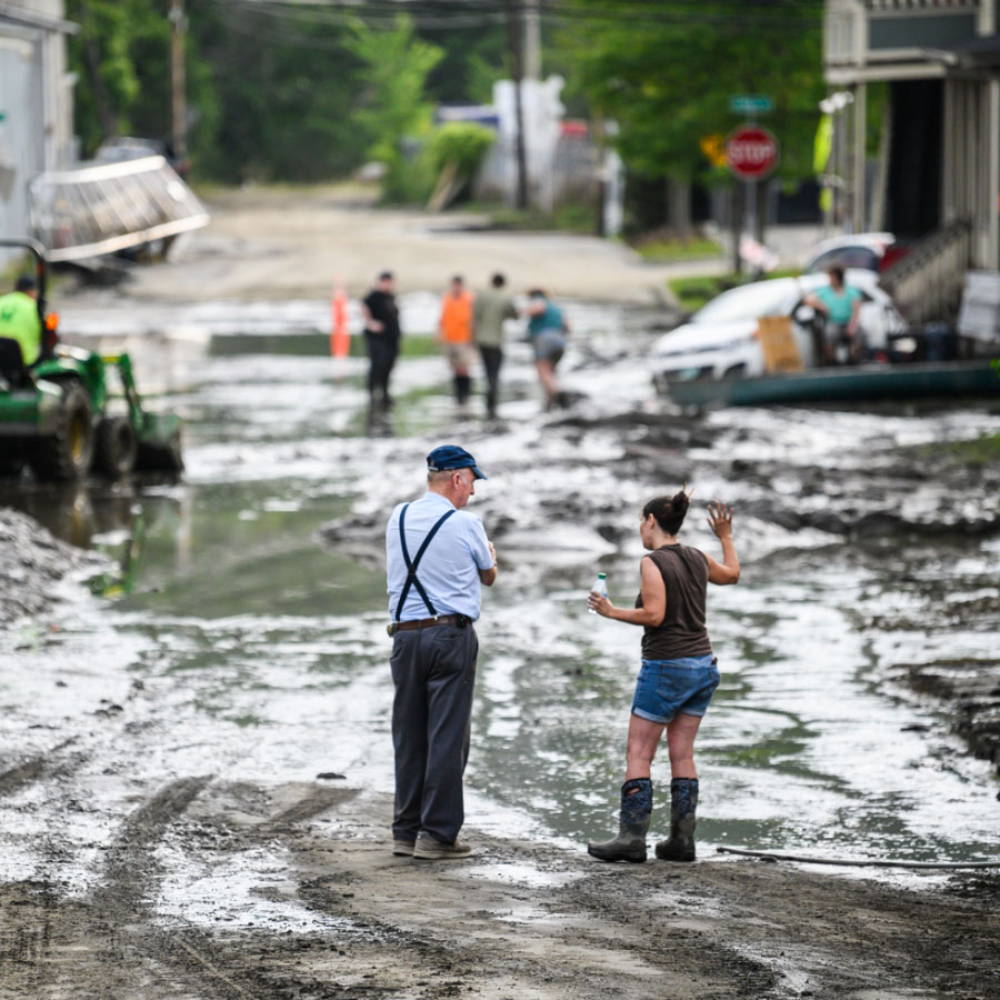 2 people surveying flooding destruction and mud in Vermont