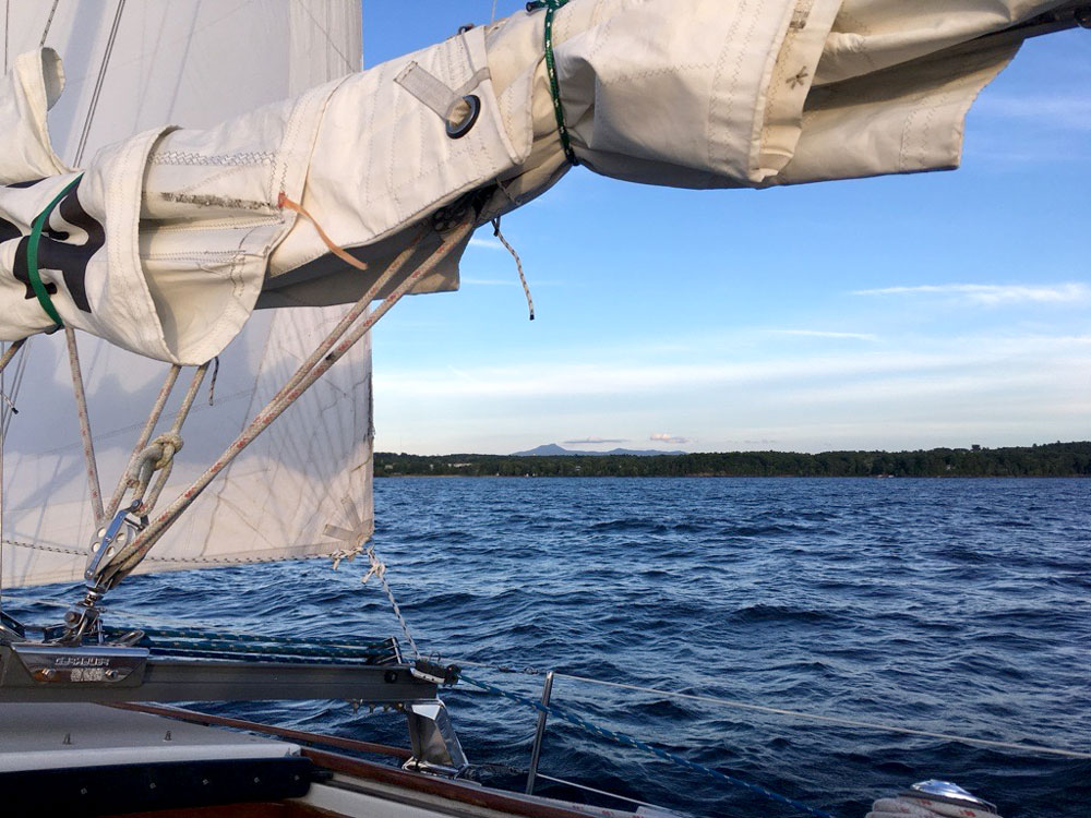 a portion of a sailboat with lake champlain in the background