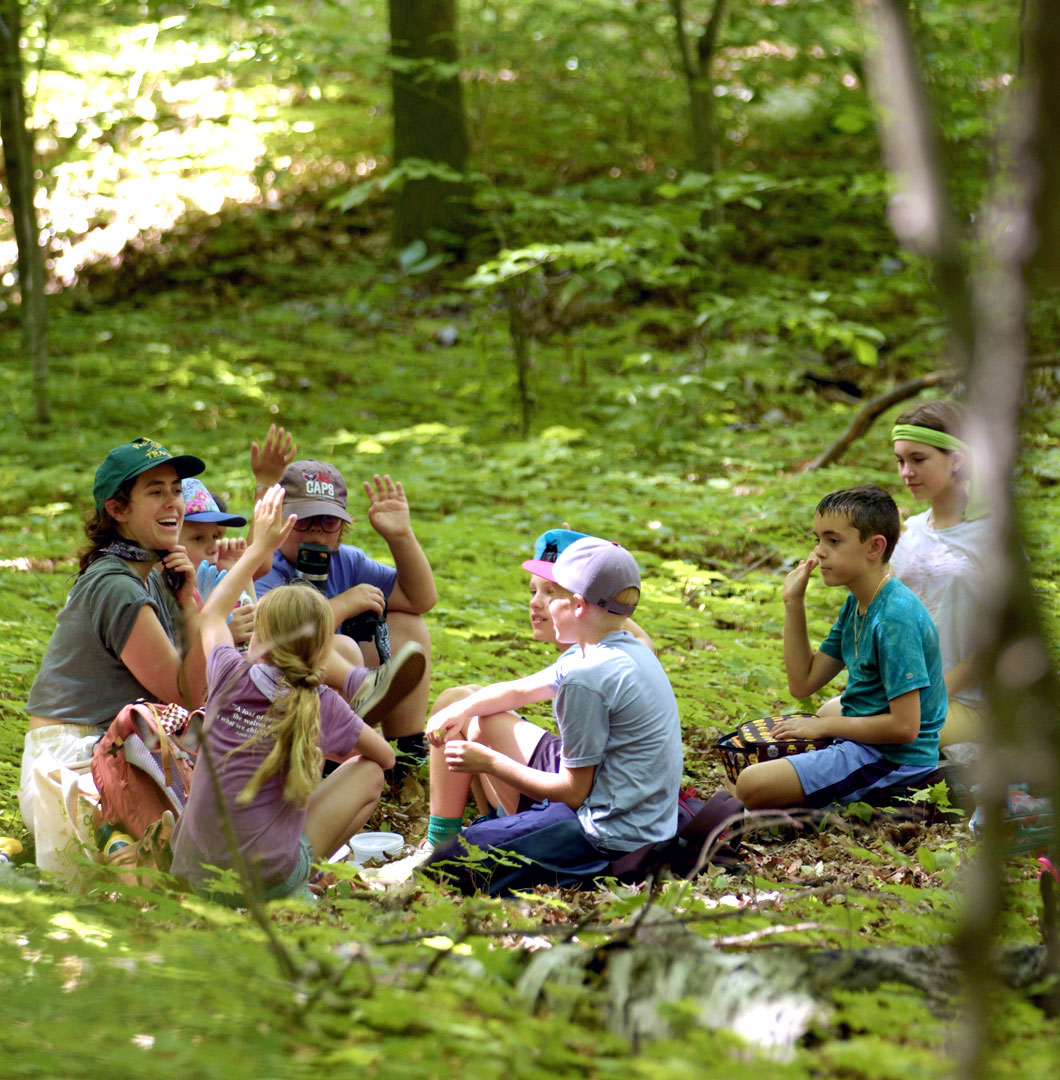 kids sitting in a circle at a summer camp in the woods