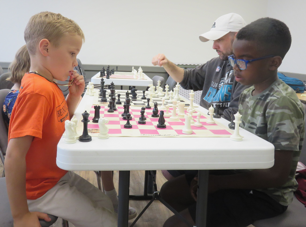 3 students and an adult playing chess