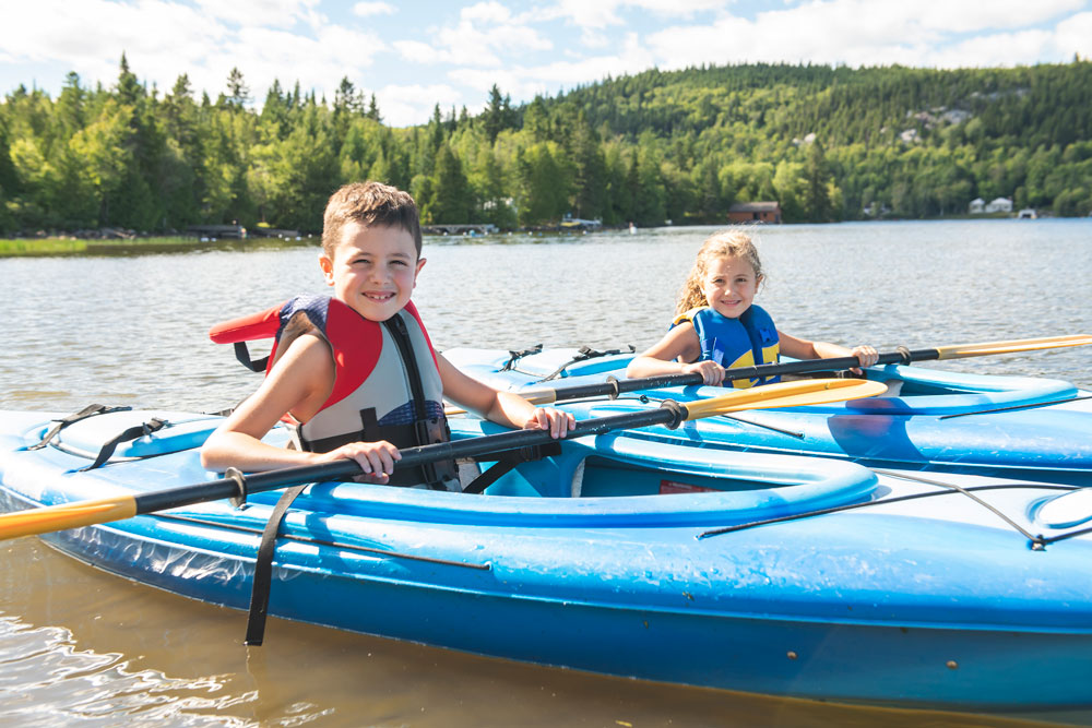 2 young children in blue kayaks on a lake in Vermont