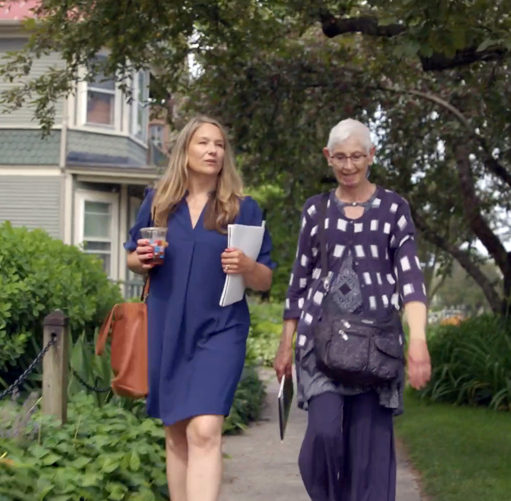 Two women walk on a sidewalk in Burlington.