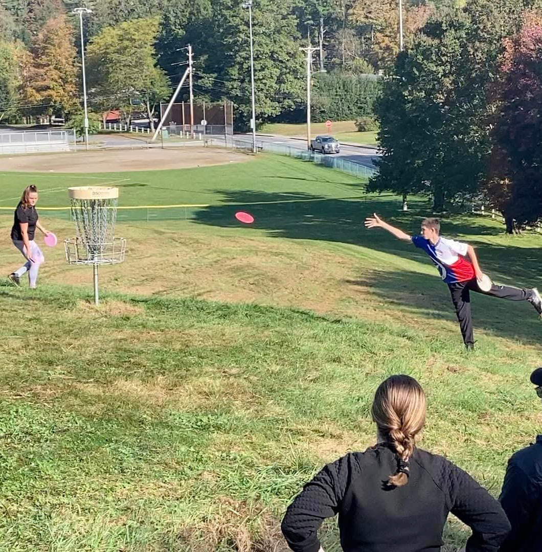Teens in a park playing disc golf