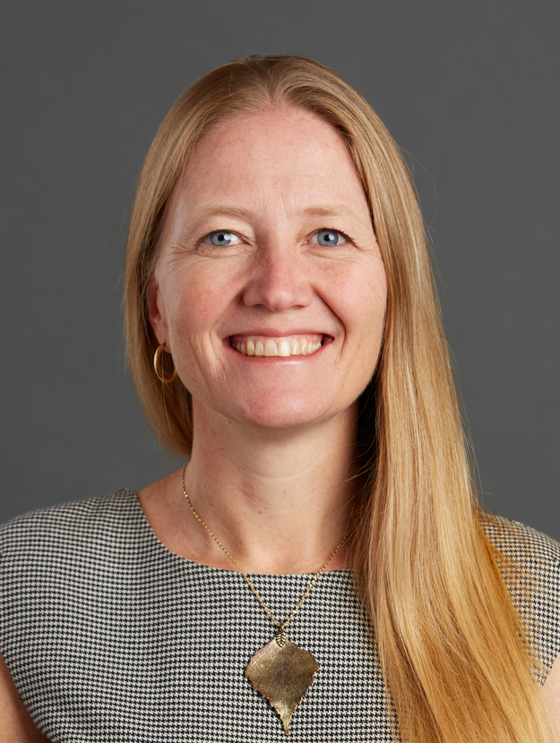 a woman with long blond hair wearing a checkered top and gold necklace