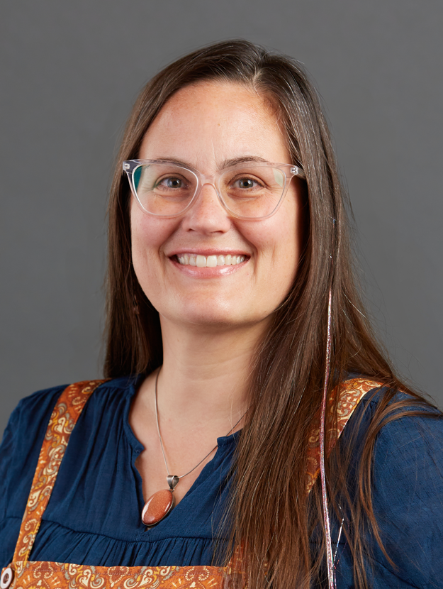 a woman with long brown hair and wearing a navy shirt and orange jumper