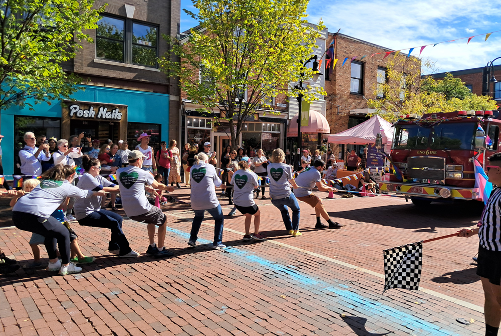 a group of people in matching shirts pulling a fire truck on a brick road