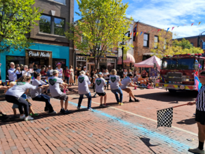 a group of people in matching shirts pulling a rope attached to a fire truck