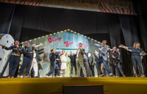 People performing on stage in front of a set with the words "Change your life"