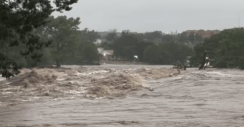 a flooded river with storm water and trees blowing
