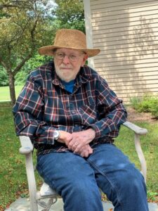 Leonard sitting in a chair outside with a sun hat