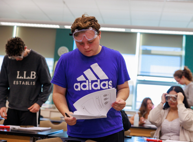 a student at CCV in science class with protective goggles on his forehead
