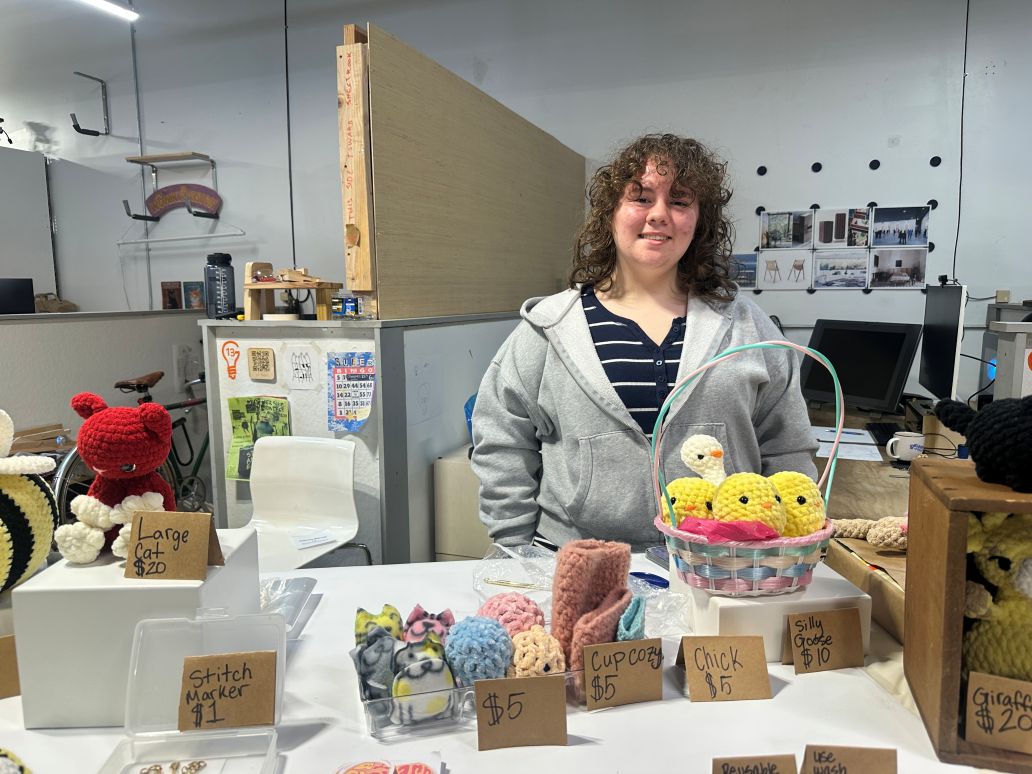 a young maker standing in front of their table at the maker market