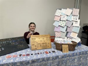 a young maker standing in front of their table at the maker market